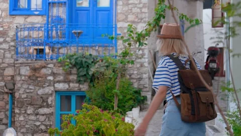 Back view of girl walking down city street with backpack in hat 库存影片 253298984