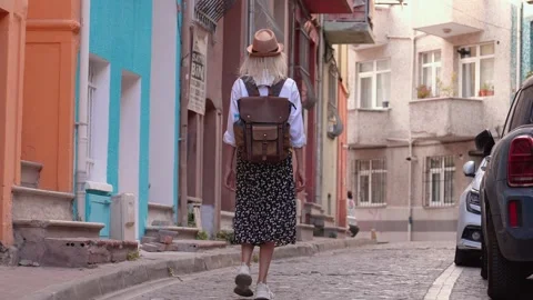 Back view of girl walking down city street with backpack in hat Vídeos de archivo 253302491
