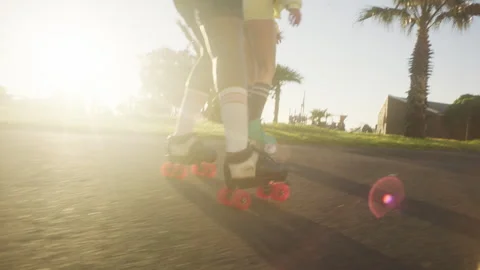 Back view of girls rollerskating next to the palm trees Stock Footage 279339914