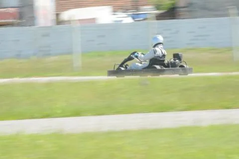 Back view of go-kart driver driving on race track on sunny day Stock Photos