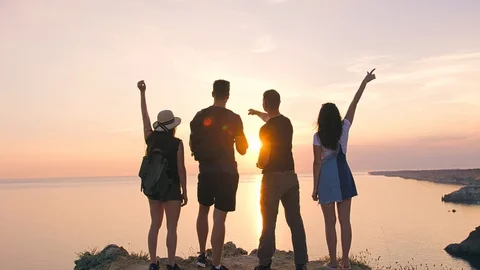 Back view group of young friends enjoying raising hands up on sunset Stockbeeldmateriaal 93216392