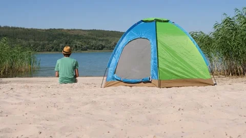 Back view guy resting alone in camping tent on green eco travel. Rear view man Vídeos de archivo 147345485