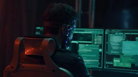 Back view of guy using futuristic headset with LED lights programs develops code Stock Photos