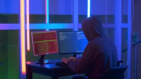 Back view of hacker dressed in a dark close working on computer 스톡 사진