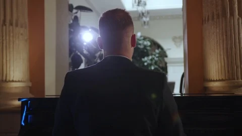 Back view of handsome man in black suit playing the piano in bright light Stock Footage 112674501