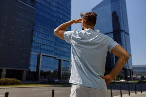 Back view of handsome man standing in modern big city and looking on glass Stock Photos
