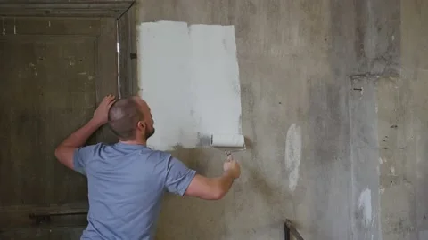 Back view of handsome Real professional house painter standing painting a grey Stock Footage 145794601