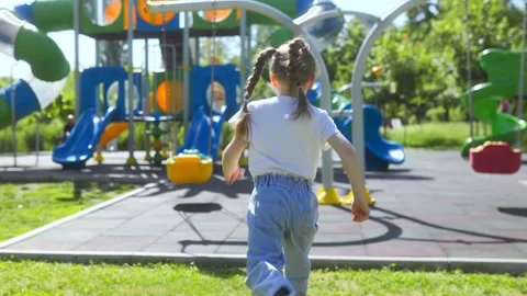 Back view of a happy child running toward swings on park playground. Stock Footage 335813937
