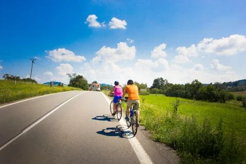 Back view at happy cyclists riding on a road on a nice summer day Stock Photos