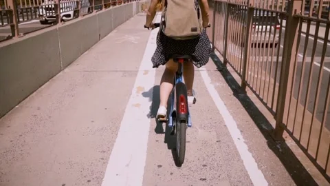 Back view happy woman with backpack riding a bicycle along a separate bike lane Stock Footage