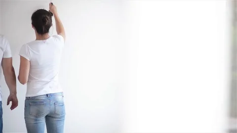 Back View of Happy Young Couple Painting the Wall with White Paint in Their Stock Footage 80968551
