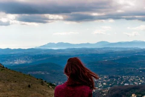 A back view head shot of an unrecognizable young redheaded woman enjoying the Stock Photos