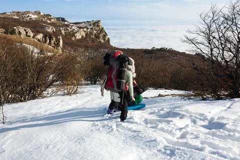 Back view of hiker with large backpack walking in snowy mountains Stock Photos
