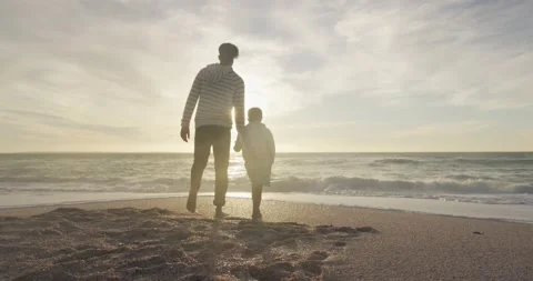 Back view of hispanic father and son walking on beach at sunset Stock Footage 167953468