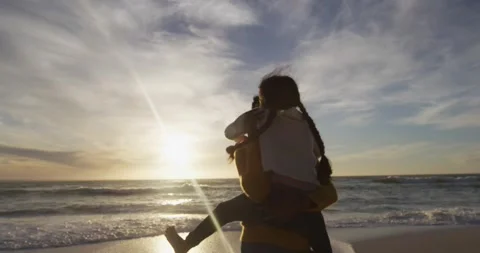 Back view of hispanic mother carrying piggyback daughter and looking at sunset Stock Footage 336608338