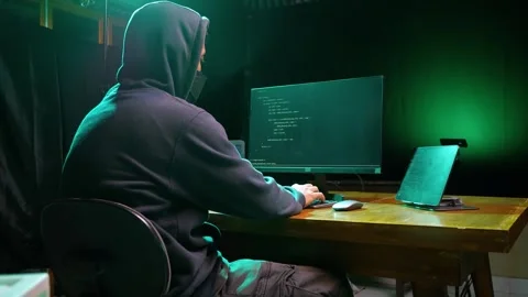 Back view of hooded computer hacker sitting at dark room in front of pc monitor Stock Footage 280178308
