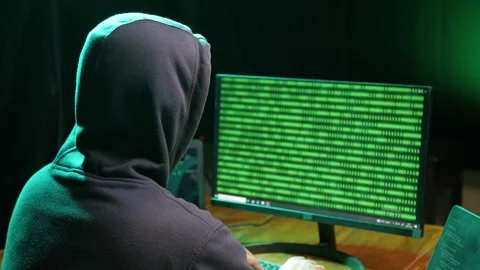 Back view of hooded computer hacker sitting at dark room in front of pc monitor Stock Footage 280178546