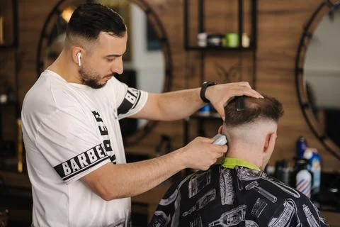 Back view of human hand hold trimmer and make hairstyle for man. Barbershop Stock-Fotos
