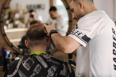 Back view of human hand hold trimmer and make hairstyle for man. Barbershop Foto stock