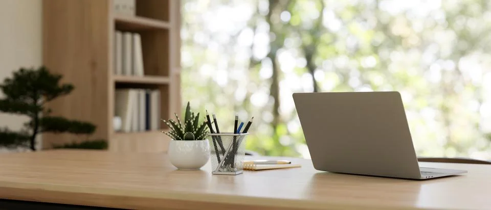 Back view image of a laptop computer on a wooden table in a contemporary pr.. Stock Photos