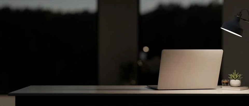 A back view image of a laptop computer on the table in a modern, dark room .. Stock Photos