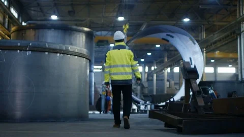 Back View of Industrial Engineer in Hard Hat Wearing Safety Jacket Walks  Stock Footage 82384003