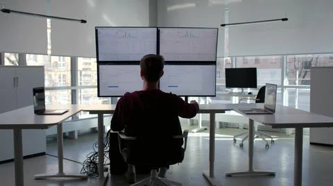Back view of it-programmer work at multi-screen computer workstation Stock-Fotos