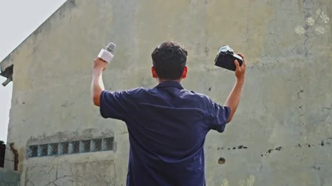 Back view of journalist raising microphone and DSLR camera in triumph against Stockbeeldmateriaal 335018052