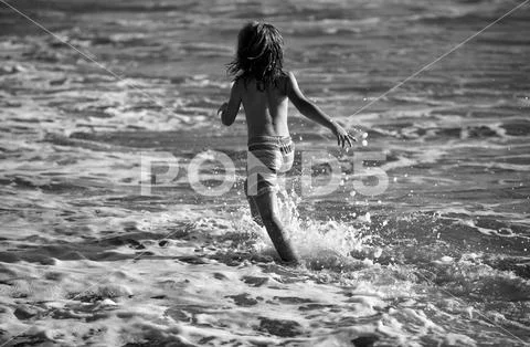 Back view of kid boy have fun on tropical sea beach. Funny child run ...