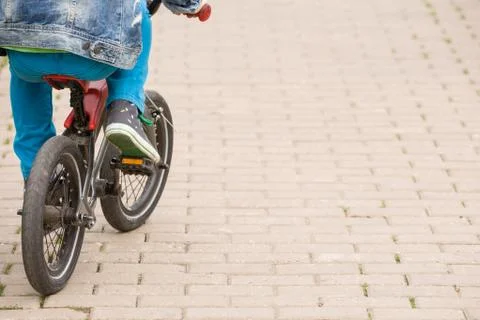 Back view on a kid boy riding on a small bicycle in the park. Stock Photos