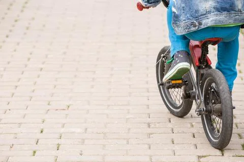 Back view on a kid boy riding on a small bicycle in the park. Child on the bi Stock Photos