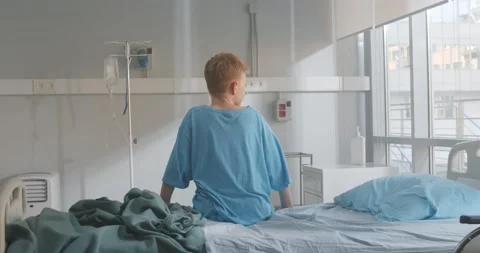 Back view of kid patient sitting on hospital bed looking out of window Stock Footage 154143564