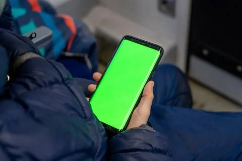 Back view of kid watch smart phone with green screen and browsing online in Stock Photos