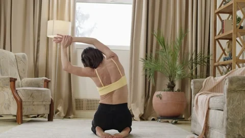 Back view of a lady with a well-toned body practicing yoga and stretching at Stock Footage 237221584