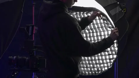 Back view of a lighting technician putting a net on a spotlight to diffuse light Stock Footage 263501752