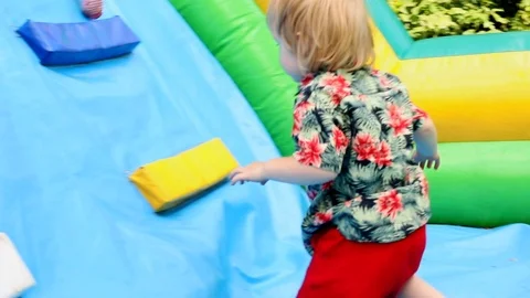 Back view of little adorable smart boy climbing up on colorful trampoline. 스톡 동영상 114013033