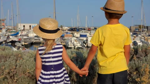 Back view of the little boy and girl holding hands on the quay of the yacht port Stock Footage 154371328