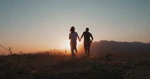 Back view of love couple silhouette running into the sunset Stock Footage 229897176