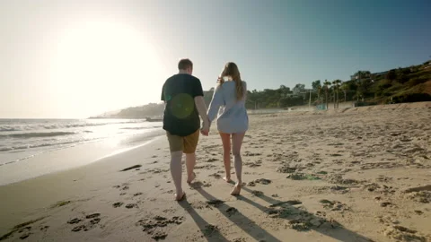 Back view of a lovely couple running towards the sea with foamy waves Stock Footage 198052226