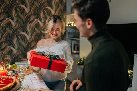 Back view of loving man making surprise, giving gift box with present to beloved Stock Photos