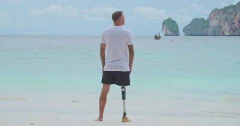 Back view male with artificial bionic leg looking at sea and blue sky in summer. Stock Footage 201369401