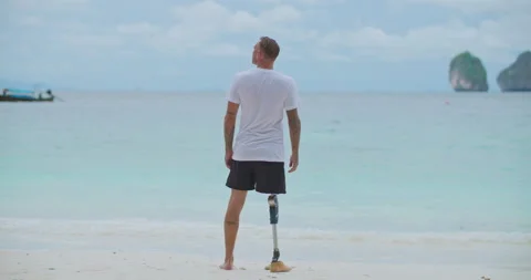 Back view male with artificial bionic leg looking at sea and blue sky in summer. Video stock 210748389
