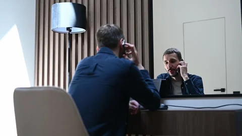 Back view of a male client sitting at a reception desk and talking on the phone Stock Footage 334010602