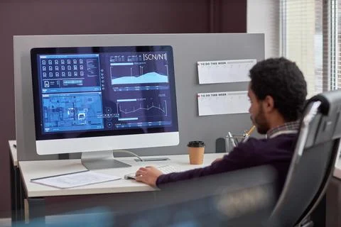 Back view at male IT engineer working with data on computer screen at workplace Foto stock
