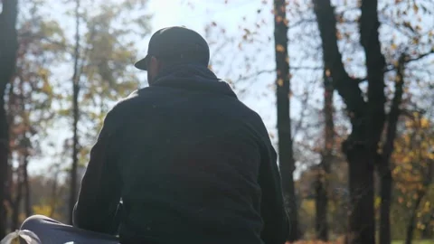 Back view. a man in a cap and with a beard sits in an autumn park Stock Footage 229859400