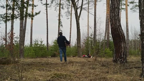 Back view of a man carrying a cut log while walking through a forest. 動画素材 334441338