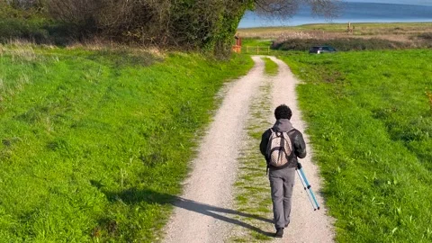 Back View Of Man Carrying Tripod While Walking On Rural Trail. drone shot Stock Footage 265440671