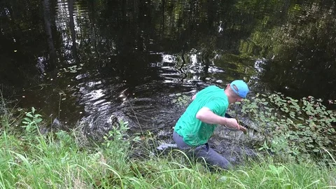 Back view of man clean pond overgrown with leaf, creeper. 4K Stock Footage 71013995
