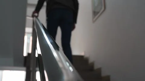 Back view of a man climbing the stairs while holding onto the handrail. Vídeo Stock 286333207
