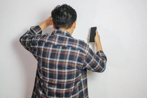 Back view of a man confused looking to the mobile phone that he hold Stock Photos
